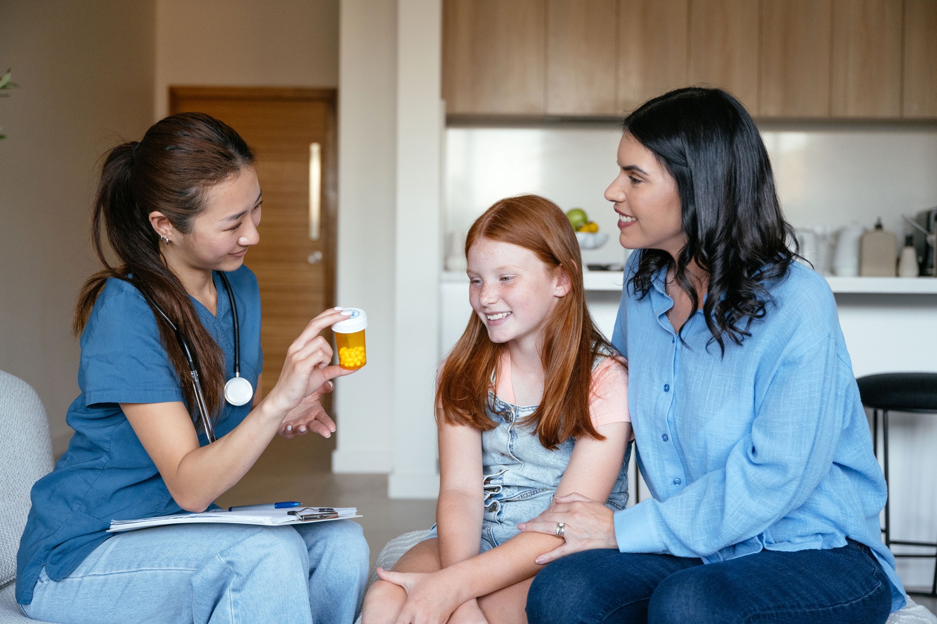 Female doctor pediatrician visiting young sick girl at home, examining her health and prescribing therapy