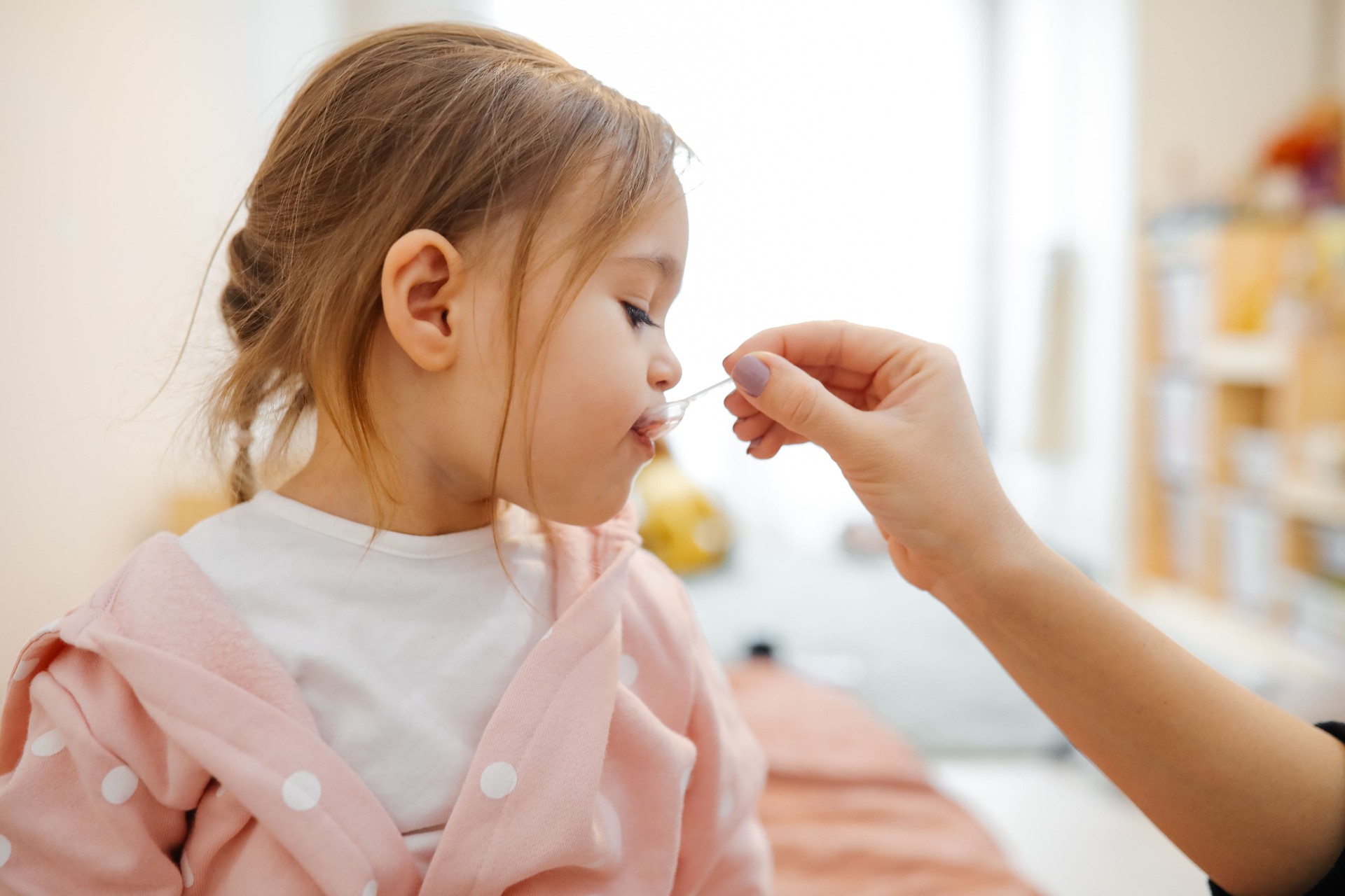 Mother giving medicine to little girl